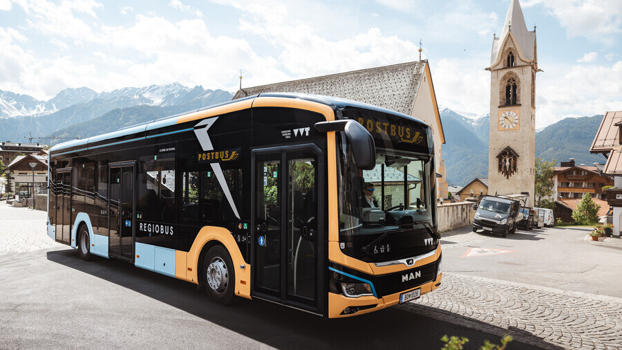 E-Bus im Dorf auf gepflasterter Straße vor Kirche