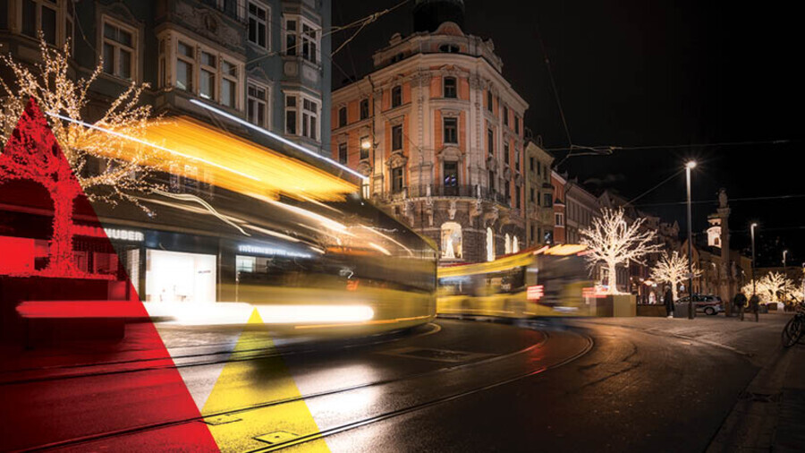 Zwei langzeitbelichtete Busse fahren durch die weihnachtlich beleuchtete Maria-Theresien-Stra&szlig;e in Innsbruck.